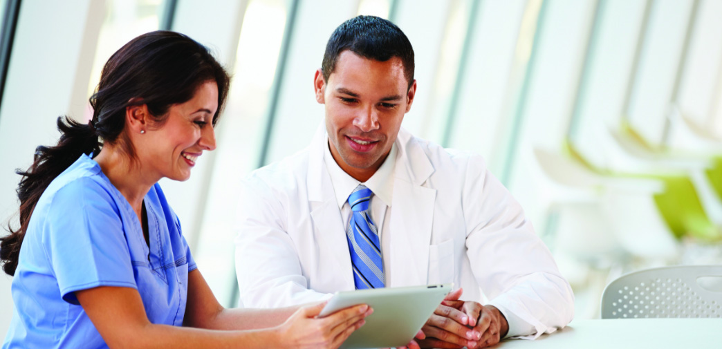 Clinician in scrubs consulting with a person in business attire.